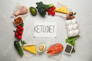 Flat lay composition with personalised keto diet products on light grey marble table