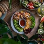 A high angle shot of keto friendly dishes: plates of salad and fresh fruits and vegetable on a wooden surface