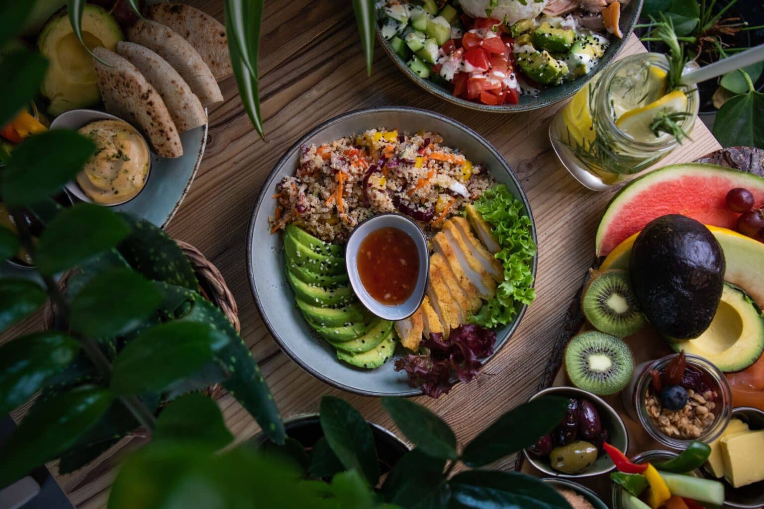 A high angle shot of keto friendly dishes: plates of salad and fresh fruits and vegetable on a wooden surface