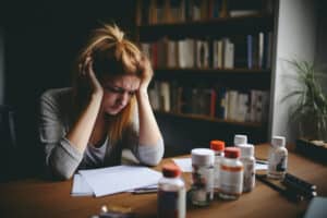 a photo of a stressed woman looking at the pills in the table