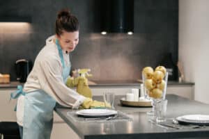 Cleaning. A woman in apron cleaning the table in the kitchen