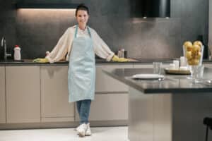 In the kitchen. Young woman in apron and gloves in the kitchen