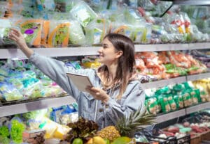 A young woman with a notebook buys groceries in the supermarket. Health food. Healthy food, organic food.