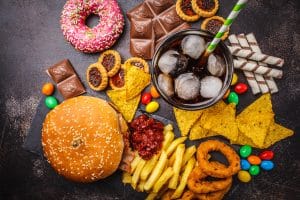 High-Carb Foods to Avoid. Fast food and sugar. Burger, sweets, chips, chocolate, donuts, soda, top view.